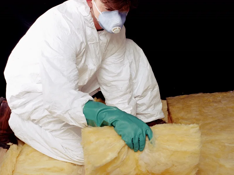 Vakman brengt isolatiedekens aan tussen de balken van een dak